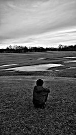 Rear view of man on field against sky