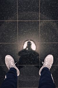 Low section of man standing on tiled floor