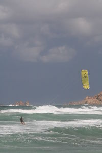 Person kiteboarding on sea against sky