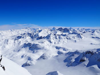 Scenic view of snow covered mountains against clear blue sky