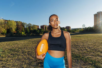 Confident american football player with sports ball in field