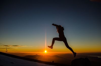 Silhouette man jumping at sunset