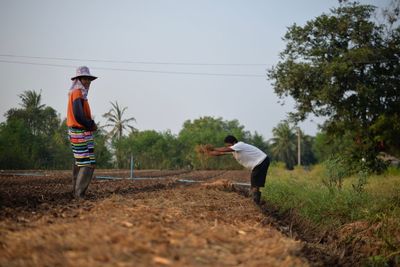 Farmers working on field against clear sky