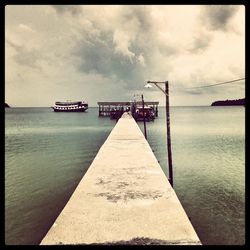 Pier on sea against cloudy sky