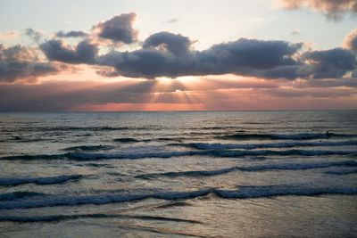 Scenic view of sea against cloudy sky at sunset
