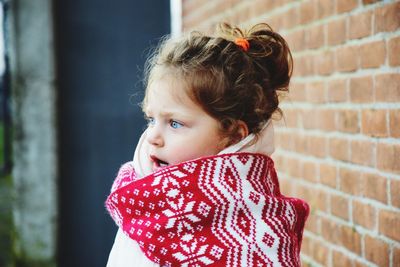 Close-up of cute baby girl against brick wall