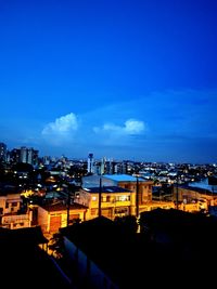 High angle view of illuminated buildings against blue sky