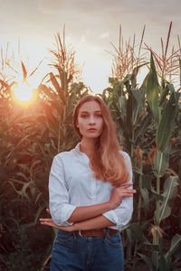 Portrait of young woman standing against plants