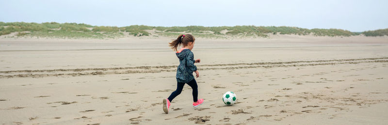 Girl playing with soccer ball at beach
