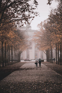 Rear view of people walking on footpath in city