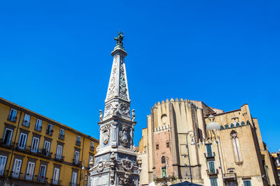 Low angle view of statue against building against clear blue sky