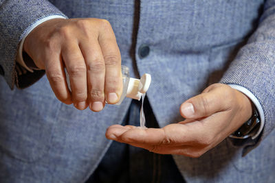 Man using wash hand sanitizer gel dispenser adopting to prevent the diffusion of the coronavirus.