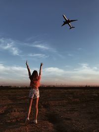 Rear view of woman looking at airplane on field