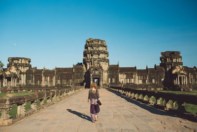 Rear view of woman standing against historic building against sky