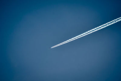 Low angle view of vapor trail against clear blue sky