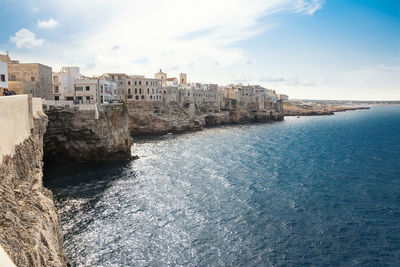 Buildings by sea against sky