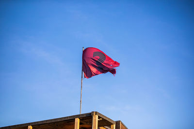 Low angle view of flag against blue sky