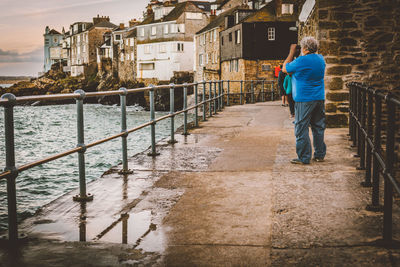 Rear view of man photographing on footbridge over river