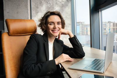 Young businesswoman using laptop while sitting on table