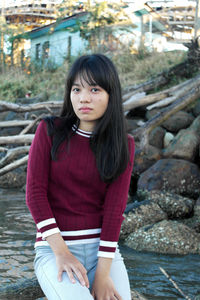 Portrait of girl sitting on wood in river