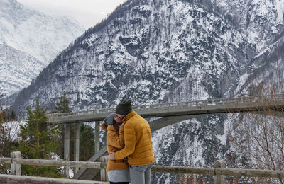 Full length of couple standing against snowcapped mountain