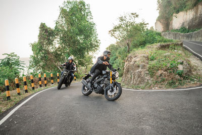 Rear view of man riding motor scooter on road