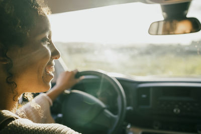 Happy young woman driving car