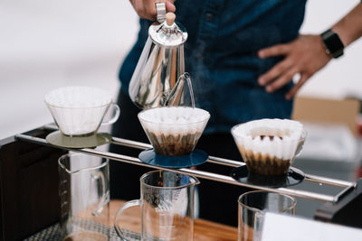 Midsection of barista pouring water in coffee cup