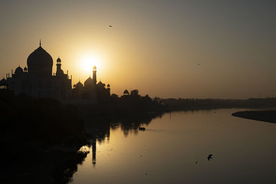 Taj mahal reflected in yamuna river at sunset in agra, india.