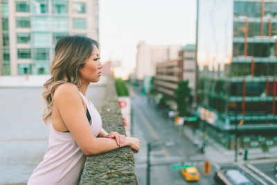 Side view of young woman standing on building terrace in city