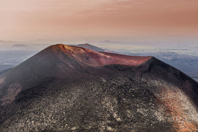 Scenic view of volcanic mountain against sky during sunset