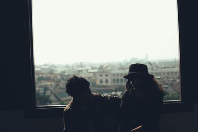 People looking at city through window