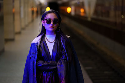 Korean hipster girl in trendy sunglasses wait for train at city metro platform travel by subway