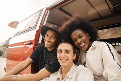 Portrait of smiling multiracial male and female friends sitting in van