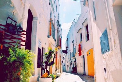 Alley in city against sky on sunny day