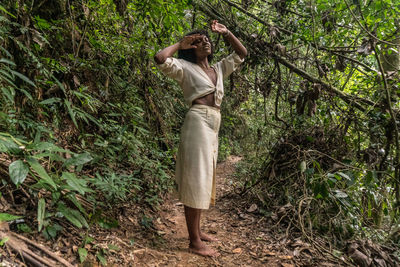 Man standing by tree in forest