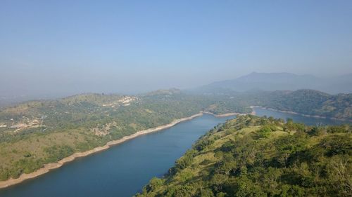 Scenic view of river by mountains against clear sky