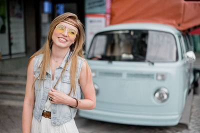 Portrait of smiling woman standing in car