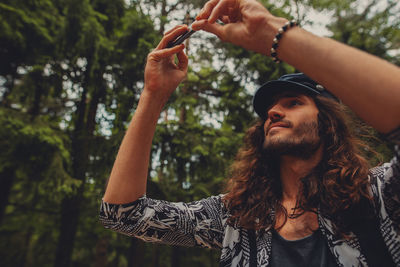 Young man photographing through smart phone against trees