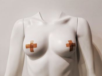 Close-up of mannequin with bandage against wall