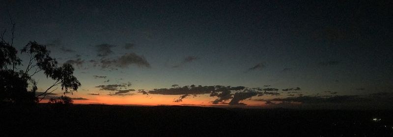 Silhouette trees on landscape against sky at sunset