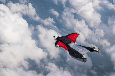 Person flying above clouds in wingsuit
