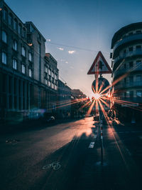 Signboard on street against buildings in city during sunset