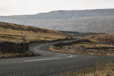 Road leading towards mountain against sky