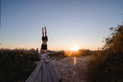 Rear view of woman against clear sky during sunset