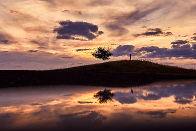 Scenic view of calm lake against cloudy sky during sunset