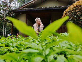 Woman blowing a kiss while standing by plants