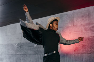 Full length of man wearing hat standing against wall