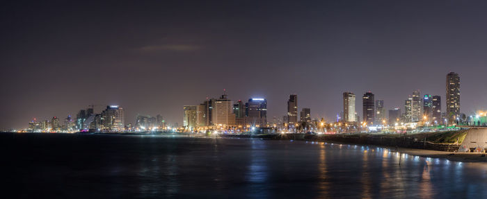 Illuminated city by river at night