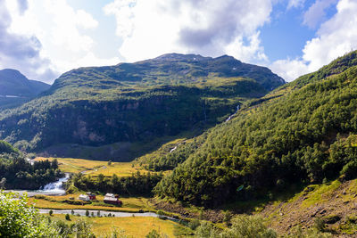 A scenic norwegian village with a river among gorgeous lush mountains against sky